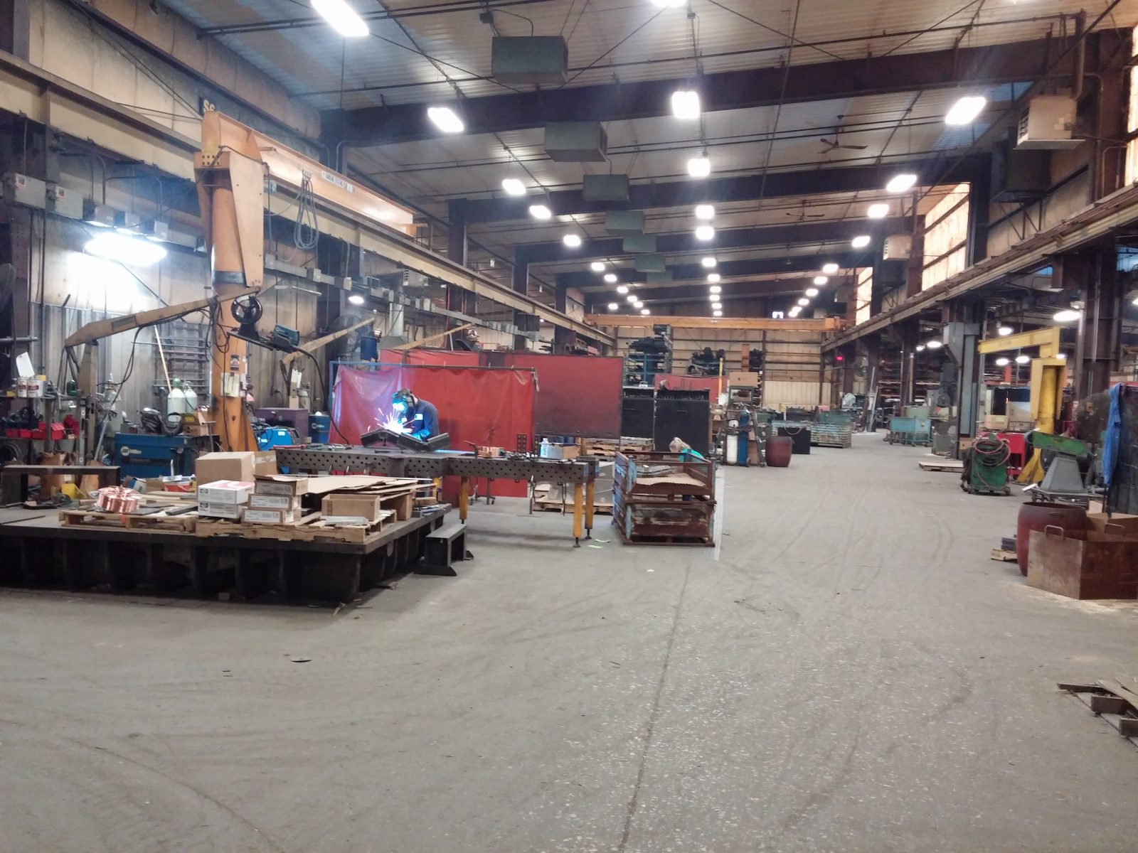 Main fabrication warehouse with worker welding